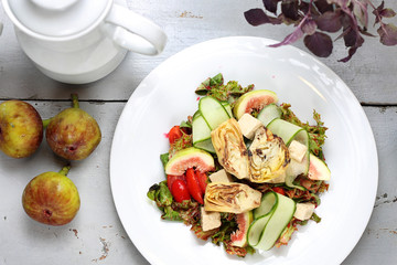 Exquisite salad with figs, artichoke, cucumber, tomatoes, feta on lamb's lettuce leaves topped with raspberry sauce.