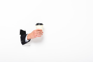 Cropped view of man holding coffee to go from hole in wall on white