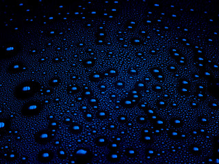 Water drops on blue background. Macro of condensation in plastic bottle. Droplets in low light close-up.