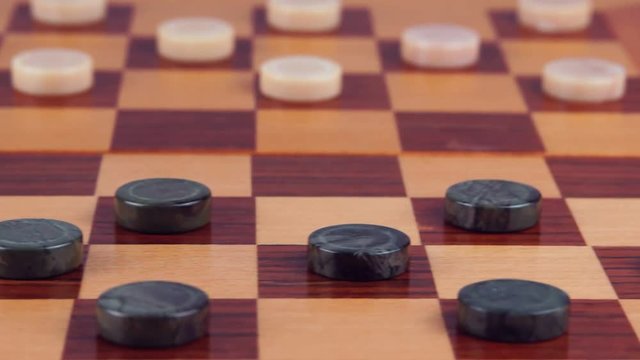 Malachite checkers and marble checkers on a wooden checkerboard. Close-up