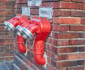 Berlin, Germany - November 29, 2018: red double watery on a brick wall view from the side