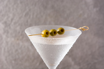 Classic Dry Martini with olives on gray stone background