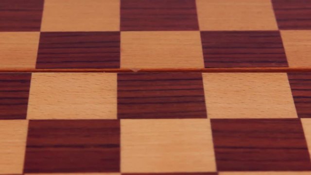 Two marble checkers on a wooden checkerboard. Close-up