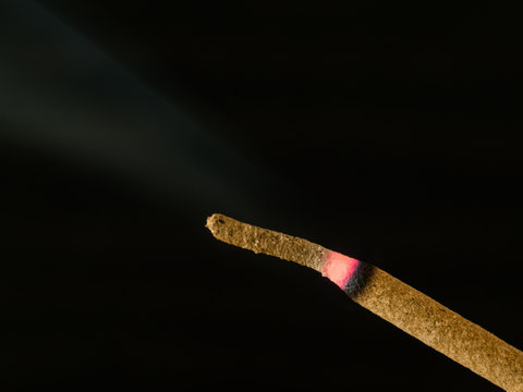 Single Incense Stick Burning, Isolated On A Black Background.