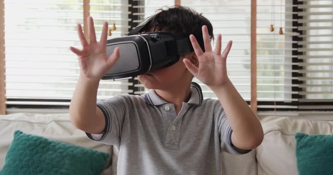 Portrait of excited boy is using VR glasses device at home. Technology concept. 4k resolution.