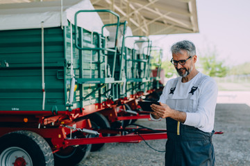 Fototapeta na wymiar worker using tablet standing in front of agricultural machinery
