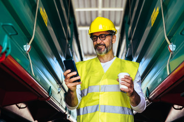 worker wearing safety wear and yellow helmet using cellphone