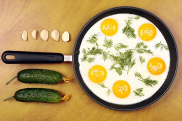 pan on the table with fried scrambled eggs with dill and cucumber, garlic