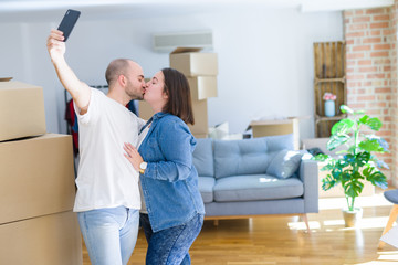 Obraz premium Young couple taking a picture photo using smartphone at new home, smiling happy for moving to new apartment