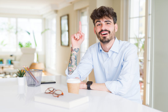 Young business man working pointing finger up with successful idea. Exited and happy. Number one.