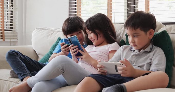 Group of children friend using smartphone together with happy emotion at home.