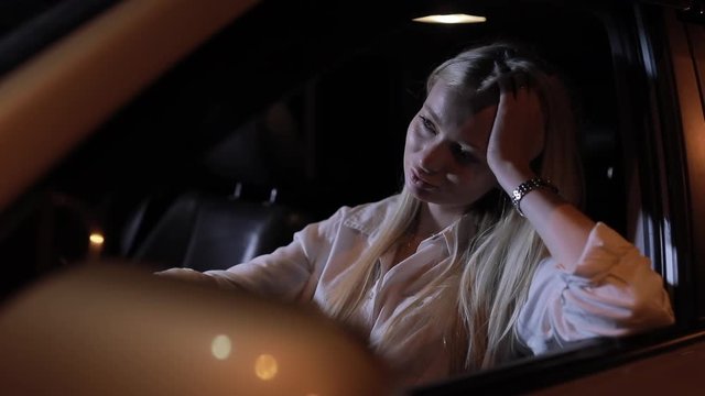 Tired woman driver sitting in car at night, slow motion