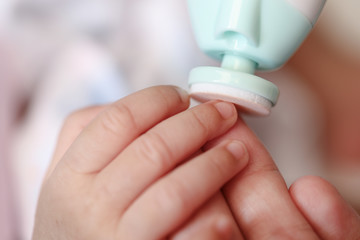 Cut nails with nail file, Mother filling baby nails using Automatic baby nail file machine.