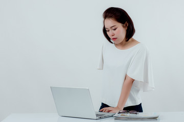 Asian beautiful woman Standing in a white shirt On the front desk, there is a laptop computer placed. Expression There is work stress. With a white background