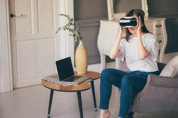 Young woman adjusting her VR headset and smiling while at home
