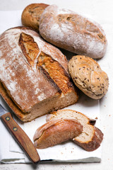 Tasty dark bread and buns  on white background, copy space. Bakery products, wholemeal bread and brown whole wheat buns