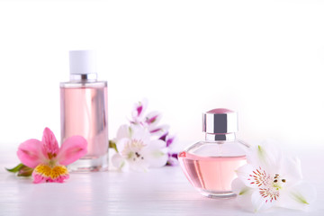 Obraz na płótnie Canvas Perfume bottles with flowers on white background, top view
