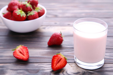Yogurt with strawberry in glass on brown wooden background