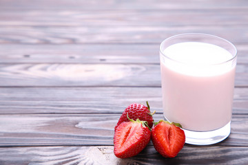 Yogurt with strawberry in glass on brown wooden background