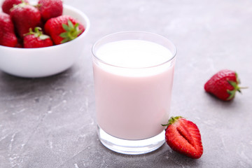 Yogurt with strawberry in glass on grey concrete background