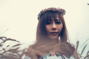 A portrait of a asian beautiful hippie girl in white dress on a field. Bohemian Style.