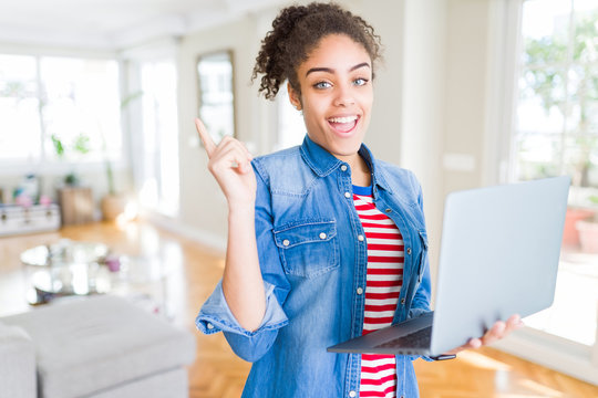 Young african american girl standing working using laptop very happy pointing with hand and finger to the side
