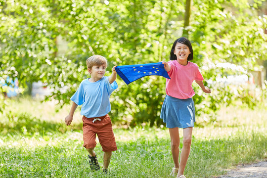 Kinder laufen mit Europa Fahne im Park