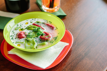 Green and red ravioli in soup for kids.
