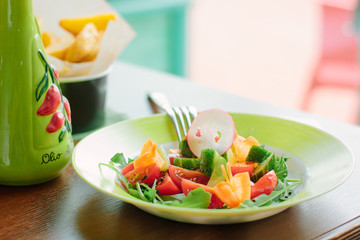 Salad with cherry potatoes, cucumber, raddish and lettuce in a green plate.