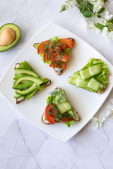 Vegetarian sandwiches with avocado, tomatoes and cucumbers on a light background