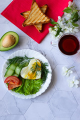 Fried eggs with lettuce, cucumber and tomato slices on a light background