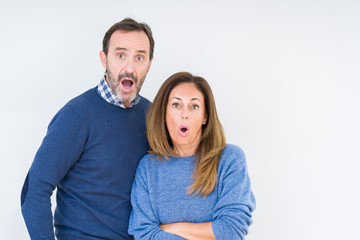 Beautiful middle age couple in love over isolated background afraid and shocked with surprise expression, fear and excited face.