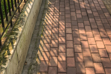 Sunlight shining on a red paved vintage pavement surface
