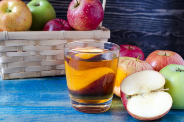 apples red and green and transparent glass of Apple juice on a wooden background side view