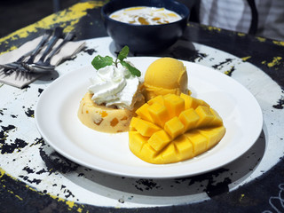 Yummy mango panna cotta and whipped cream with sliced fresh ripe mango and mango sorbet icecream.