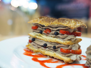 Mille feuille - Slice of puff cake with strawberry, blueberry and chocolate whipped cream; topped with cocoa powder.  Served with strawberry granita and frozen yogurt, French dessert.
