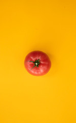 Close up ripe tomato on bright yellow background top view flat lay. Summer abstract background with tomato