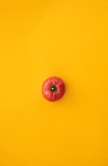 Close up ripe tomato on bright yellow background top view flat lay. Summer abstract background with tomato