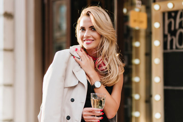 Excited blonde woman in trendy silver wristwatch posing with pleasure in her birthday, holding...