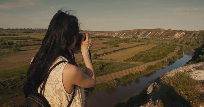 Young female tourist taking a photo of a picturesque canyon in the summer.
