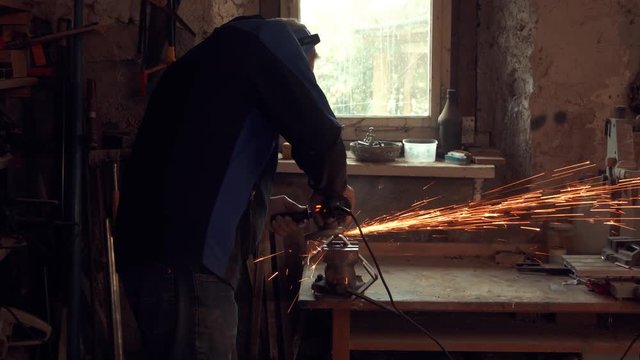 worker grinding metal part in old workshop