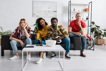 upset multicultural friends watching championship in living room