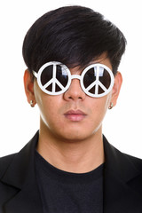 Face of cool handsome Asian man wearing sunglasses with peace si