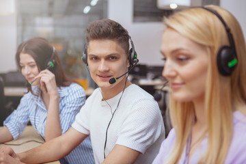 Young people working at call center, wearing headsets with microphones, answering calls. Handsome...