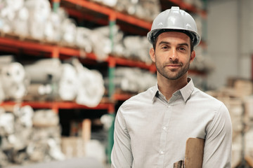 Smiling foreman wearing a hard hat on his warehouse floor