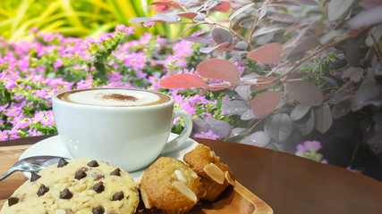 Coffee and dessert on a wooden table with a tree backdrop Flowers that are blooming