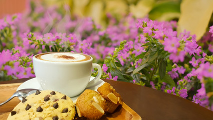 Coffee and dessert on a wooden table with a tree backdrop Flowers that are blooming