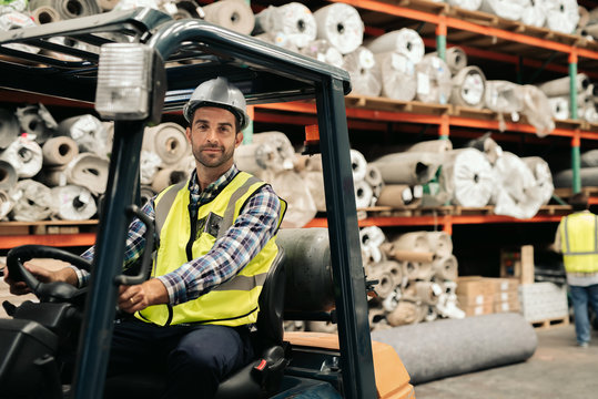Smiling worker using a forklift to move warehouse stock