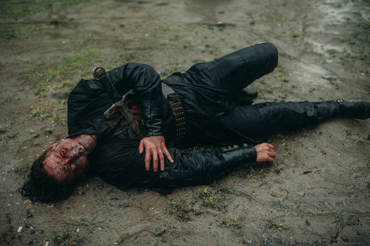 A young man in the image of a murdered medieval knight lying on the ground.