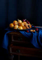 Still life with fresh medlar and cherry on the metallic plate